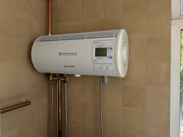White electric storage water heater on a tiled bathroom wall